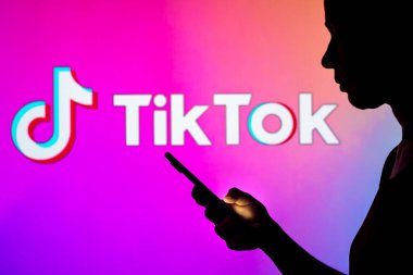 28 Mart 2022, Brezilya. Bu resimde, bir kadının siluetinde arka planda TikTok logosu olan bir akıllı telefon var.