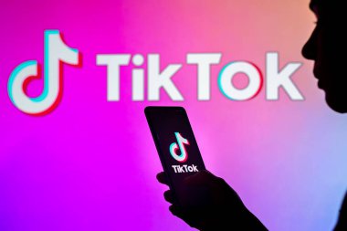 28 Mart 2022, Brezilya. Bu resimde, bir kadının silueti ekranda ve arka planda TikTok logosunun gösterildiği bir akıllı telefon tutuyor.