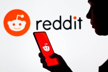 28 Mart 2022, Brezilya. Bu resimde, bir kadının silueti ekranda ve arka planda Reddit logosunun gösterildiği bir akıllı telefon tutuyor.
