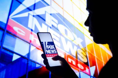 30 Mart 2022, Brezilya. Bu resimde, bir kadının silueti ekranda ve arka planda Fox News kanalının logosunun gösterildiği bir akıllı telefon tutuyor.
