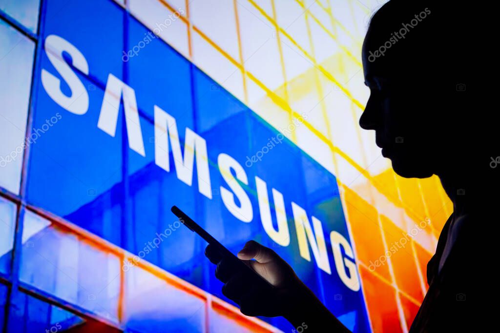 March, 30 2022, Brazil. In this photo illustration, a woman's silhouette holds a smartphone with the Samsung Electronics logo in the background