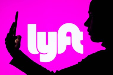 1 Nisan 2022, Brezilya. Bu resimde, bir kadının siluetinde arka planda Lyft logosu olan bir akıllı telefon var.