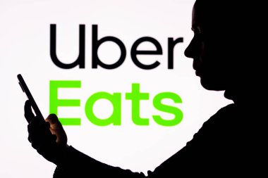 1 Nisan 2022, Brezilya. Bu resimde, arka planda Uber Eats logosu olan bir kadın silueti var.