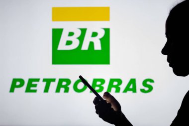 4 Nisan 2022, Brezilya. Bu resimde, bir kadının siluetinde arka planda Petrleo Brasileiro S.A. (Petrobras) logosu bulunan bir akıllı telefon bulunur..