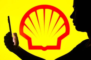 4 Nisan 2022, Brezilya. Bu resimde, bir kadının siluetinde arka planda Shell logosu olan bir akıllı telefon var.