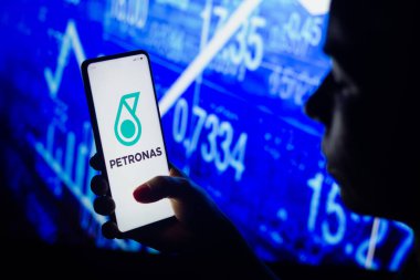 4 Nisan 2022, Brezilya. Bu resimde, bir kadının silueti ekranında Petronas logosu olan bir akıllı telefon tutuyor.