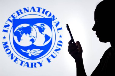6 Nisan 2022, Brezilya. Bu resimde, bir kadının silueti arkasında Uluslararası Para Fonu (IMF) logosu bulunan bir akıllı telefon tutuyor.