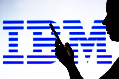 10 Nisan 2022, Brezilya. Bu resimde, arka planda Uluslararası İş Makineleri Şirketi (IBM) logosu olan bir kadın silueti yer alıyor.