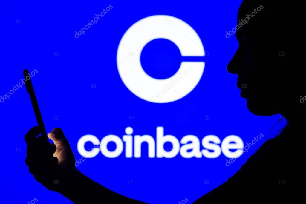 April 12, 2022, Brazil. In this photo illustration, a woman's silhouette holds a smartphone with the Coinbase logo in the background