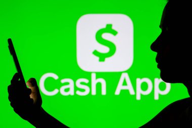 21 Nisan 2022, Brezilya. Bu resimde Cash App logosu cep telefonu tutan siluet bir kadının arka planında görülüyor.