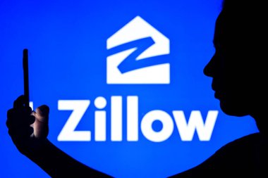 22 Nisan 2022, Brezilya. Bu resimde Zillow Grup logosu arka planda siluetli bir kadının cep telefonu tutarken görülüyor.