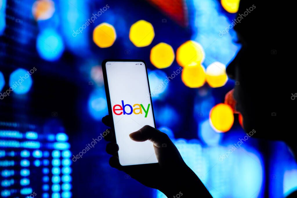 April 22, 2022, Brazil. In this photo illustration, a silhouetted woman holds a smartphone with the eBay logo displayed on the screen