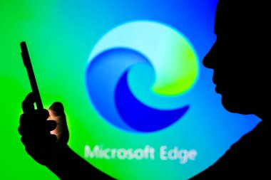 27 Nisan 2022, Brezilya. Bu resimde, Microsoft Edge logosu siluetli bir kadının elinde cep telefonu ile arka planda görülüyor.