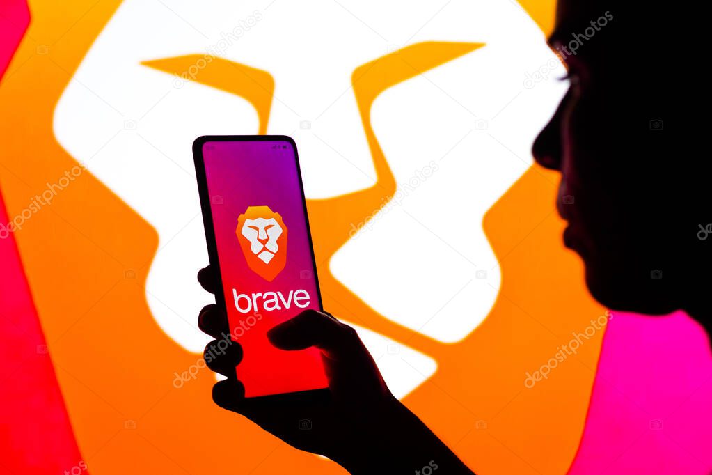 April 27, 2022, Brazil. In this photo illustration, a silhouetted woman holds a smartphone with the Brave logo displayed on the screen