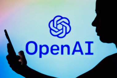 2 Mayıs 2022, Brezilya. Bu resimde, OpenAI logosu elinde cep telefonu olan siluetli bir kadının arka planında görülüyor.