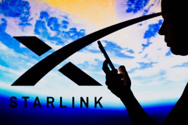 2 Mayıs 2022, Brezilya. Bu resimde, Starlink logosu siluetli bir kadının elinde cep telefonu ile arka planda görülüyor.