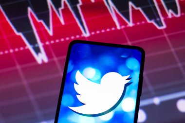 4 Mayıs 2022, Brezilya. Bu fotoğraf illüstrasyonunda, Twitter logosu arka planda borsanın grafik temsili ile akıllı telefon ekranında görüntülendi