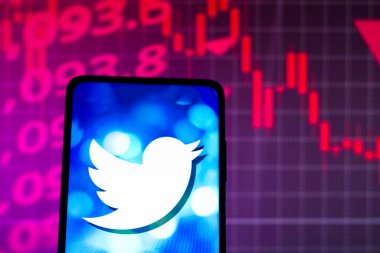 4 Mayıs 2022, Brezilya. Bu fotoğraf illüstrasyonunda, Twitter logosu arka planda borsanın grafik temsili ile akıllı telefon ekranında görüntülendi