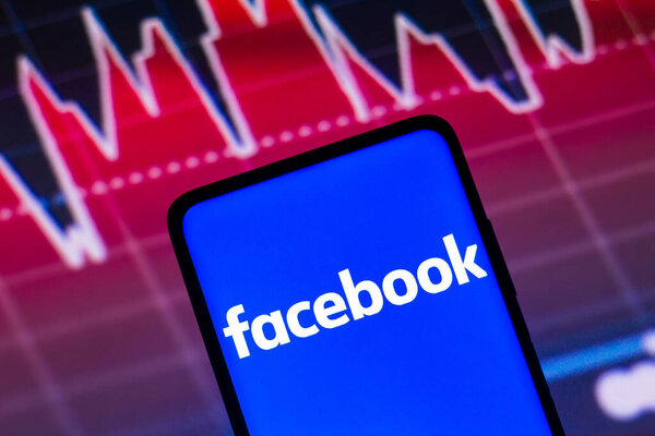 May 4, 2022, Brazil. In this photo illustration the Facebook logo seen displayed on a smartphone screen, with graphic representation of the stock market in the background