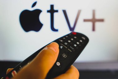 May 10, 2022, Brazil. In this photo illustration a close-up of a hand holding a TV remote control seen in front of the Apple TV+ (Plus) logo