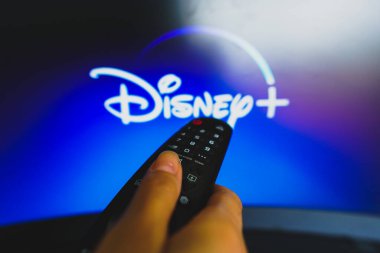 10 Mayıs 2022, Brezilya. Bu resimde, Disney Plus logosu önünde görülen uzaktan kumandayı tutan bir elin yakın çekimi var.