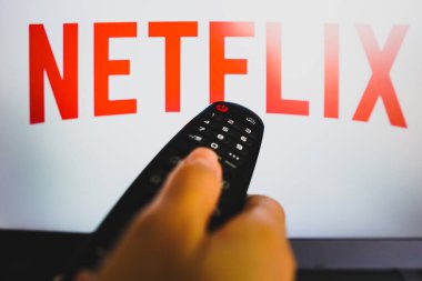 May 10, 2022, Brazil. In this photo illustration a close-up of a hand holding a TV remote control seen in front of the Netflix logo