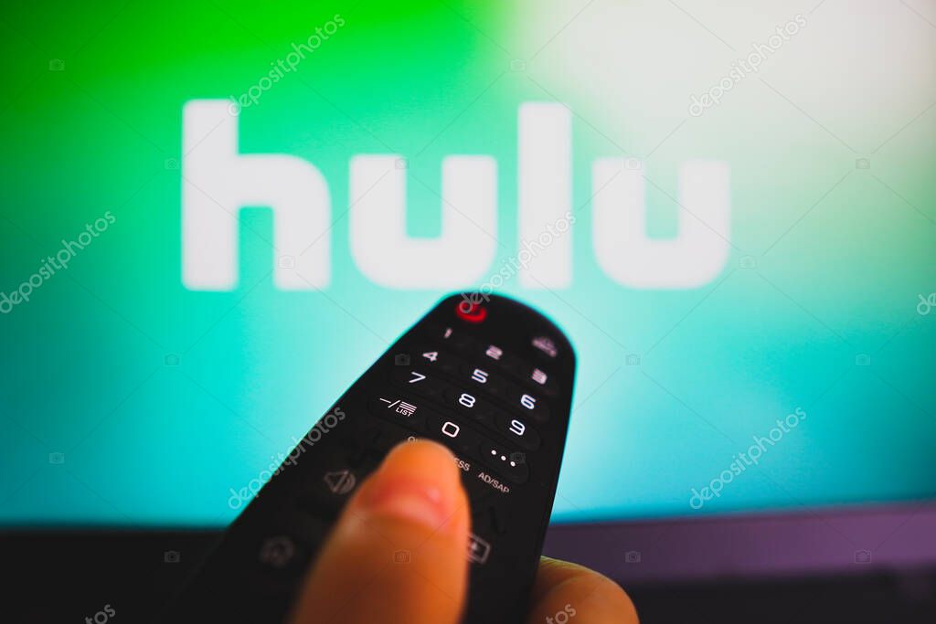 May 10, 2022, Brazil. In this photo illustration a close-up of a hand holding a TV remote control seen in front of the Hulu logo