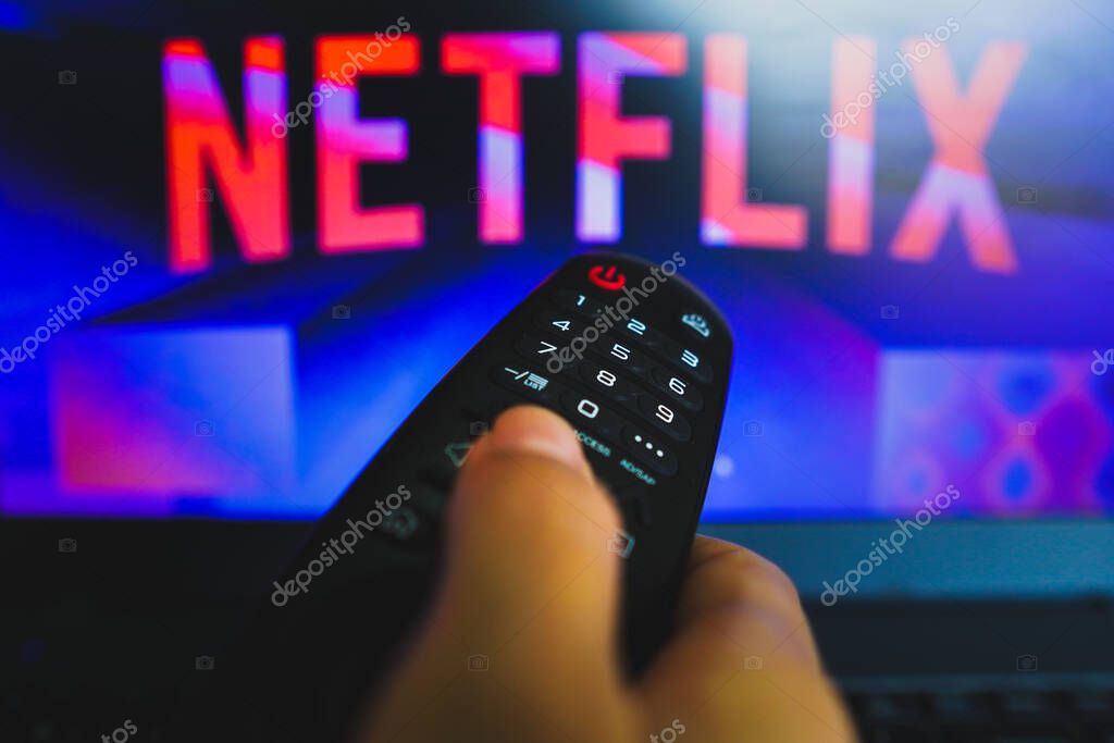 May 10, 2022, Brazil. In this photo illustration a close-up of a hand holding a TV remote control seen in front of the Netflix logo