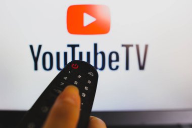 10 Mayıs 2022, Brezilya. Bu resimde, YouTube TV logosu önünde görülen uzaktan kumandayı tutan bir elin yakın çekimi görülüyor.