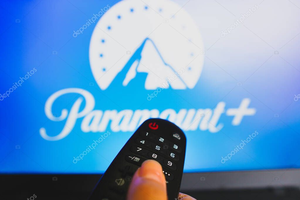 May 10, 2022, Brazil. In this photo illustration a close-up of a hand holding a TV remote control seen in front of the Paramount Plus logo