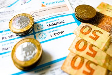 19 Mayıs 2022, Brezilya. Bir elektrik faturası (elektrik), Brezilya Real Real 'in banknotları ve sikkeleri ile 175 kilovat saat (kWsaat) aylık tüketimini gösterir