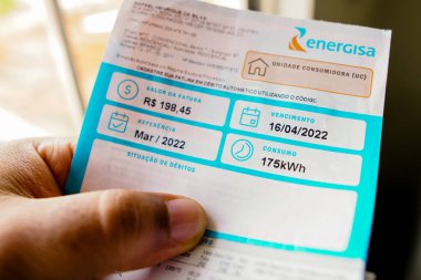 19 Mayıs 2022, Brezilya. Bir elektrik faturası (ışık) tutan tüketici, aylık 175 kilovat saat (kWsaat) tüketimini gösterir)