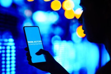 30 Mayıs 2022, Brezilya. Bu resimde, siluetli bir kadın ekranda Tata Motors Limited logosunu gösteren bir akıllı telefon tutuyor.