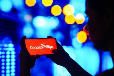 30 Mayıs 2022, Brezilya. Bu resimde siluetli bir kadın ekranda ConocoPhilips logosu olan bir akıllı telefon tutuyor.