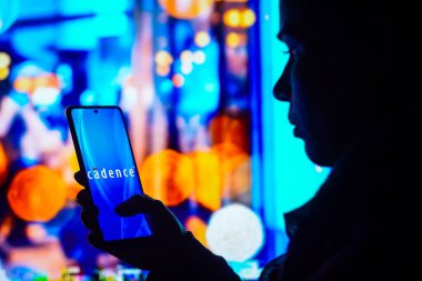 31 Mayıs 2022, Brezilya. Bu resimde, siluetli bir kadın ekranda Cadence Tasarım Sistemleri logosunun sergilendiği bir akıllı telefon tutuyor.