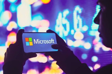 1 Haziran 2022, Brezilya. Bu resimde, siluetli bir kadın ekranda Microsoft Corporation logosunun sergilendiği bir akıllı telefon tutuyor.