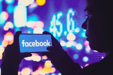 1 Haziran 2022, Brezilya. Bu resimde, siluetli bir kadın ekranında Facebook logosu olan bir akıllı telefon tutuyor.