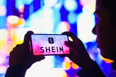 4 Haziran 2022, Brezilya. Bu resimde, siluetli bir kadın ekranında Shein logosu olan bir akıllı telefon tutuyor.