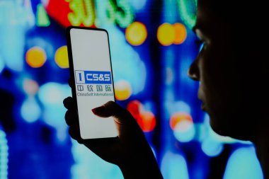 6 Haziran 2022, Brezilya. Bu resimde siluetli bir kadın ekranda Chinasoft International logosu olan bir akıllı telefon tutuyor.
