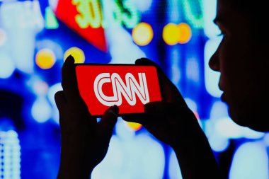 June 6, 2022, Brazil. In this photo illustration, a silhouetted woman holds a smartphone with the Cable News Network (CNN) logo displayed on the screen clipart