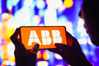 7 Haziran 2022, Brezilya. Bu resimde, siluetli bir kadın ekranda Asea Brown Boveri (ABB) logosunu gösteren bir akıllı telefon tutuyor.