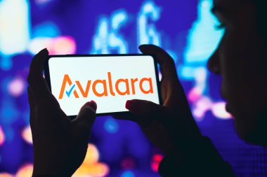 11 Haziran 2022, Brezilya. Bu resimde siluetli bir kadın ekranında Avalara logosu olan bir akıllı telefon tutuyor.