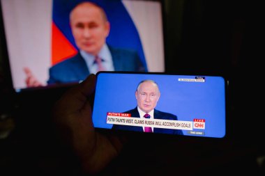 18 Haziran 2022, Brezilya. Bir kişi, Rusya Devlet Başkanı Vladimir Putin 'in canlı yayını ABD' den CNN TV kanalı üzerinden izliyor. Putin Batı 'yı kışkırttı ve Rusya' nın belirlenen hedefleri karşılayacağını söyledi