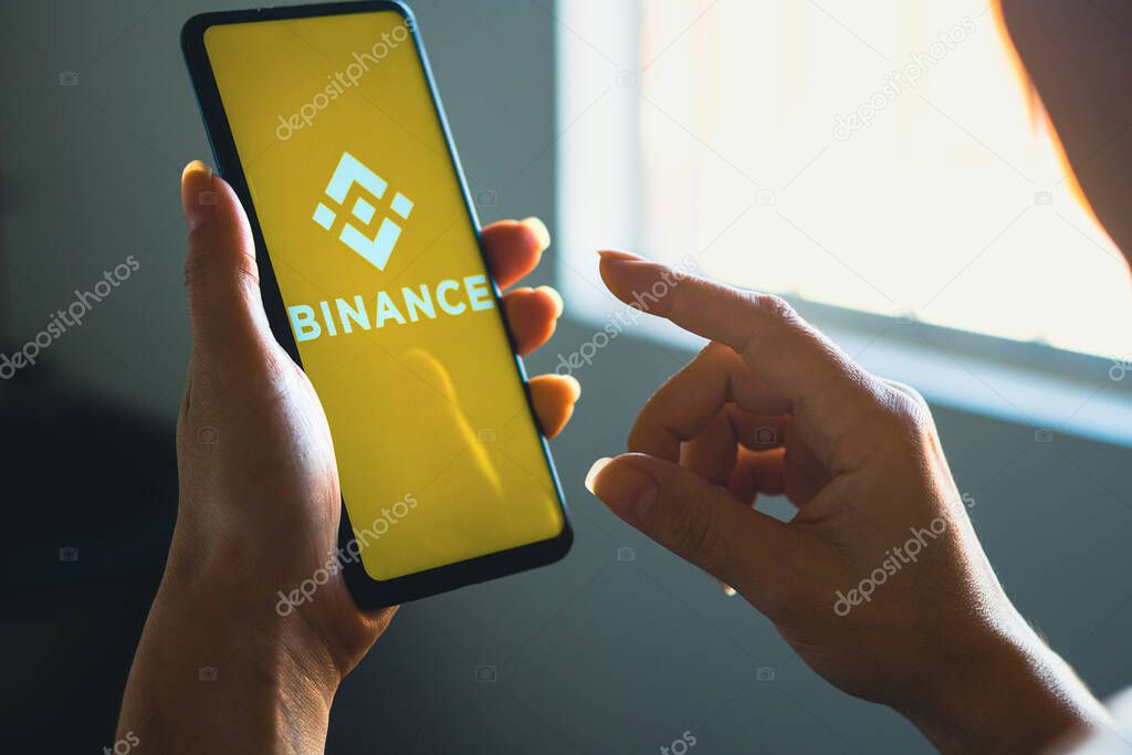 June 26, 2022, Brazil. In this photo illustration, a woman's holds a smartphone with the Binance Coin (BNB) logo displayed on the screen