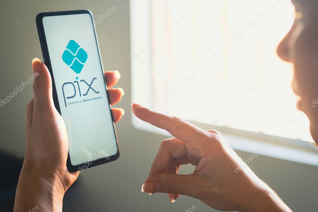 June 26, 2022, Brazil. In this photo illustration, a woman's holds a smartphone with the PIX logo displayed on the screen