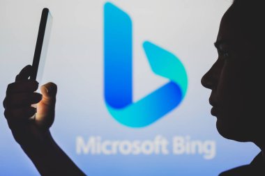 June 29, 2022, Brazil. In this photo illustration, the Microsoft Bing logo is seen in the background of a silhouetted woman holding a mobile phone