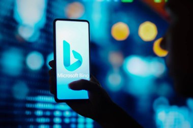 June 29, 2022, Brazil. In this photo illustration, a silhouetted woman holds a smartphone with the Microsoft Bing logo displayed on the screen