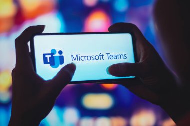 6 Temmuz 2022, Brezilya. Bu resimde siluetli bir kadın ekranda Microsoft Ekip logosu olan bir akıllı telefon tutuyor.