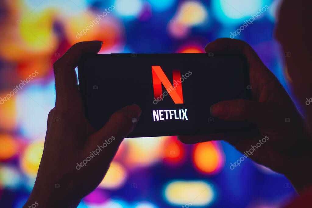 July 6, 2022, Brazil. In this photo illustration, a silhouetted woman holds a smartphone with the Netflix logo displayed on the screen
