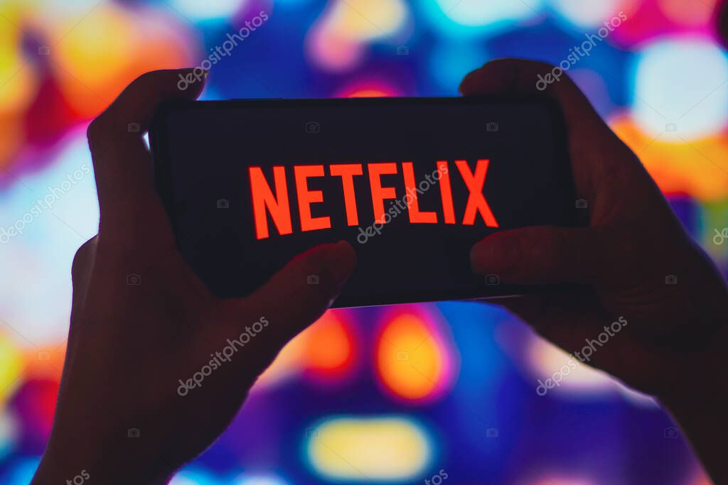 July 6, 2022, Brazil. In this photo illustration, a silhouetted woman holds a smartphone with the Netflix logo displayed on the screen